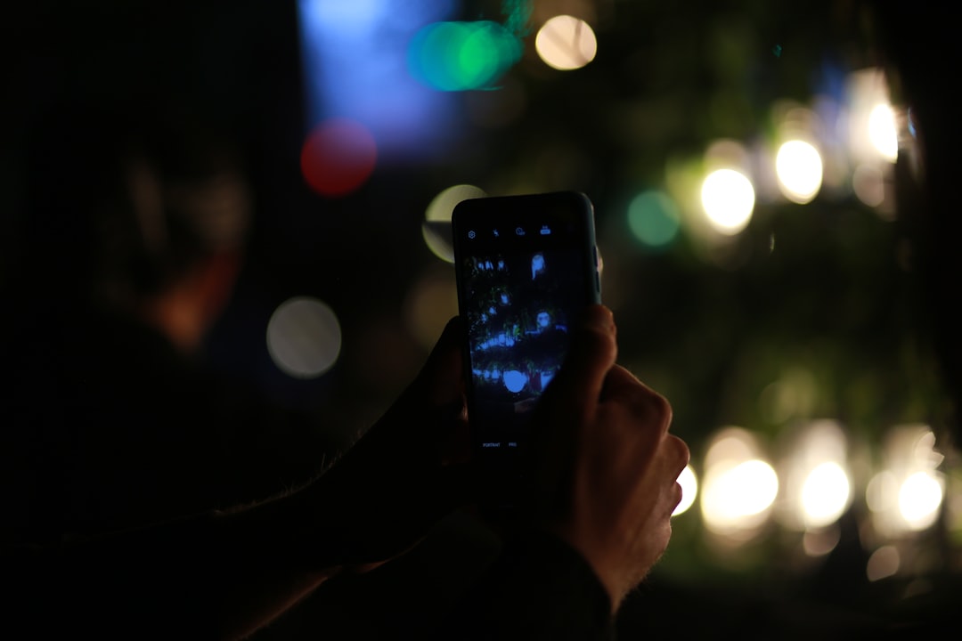person holding black smartphone taking photo of city lights