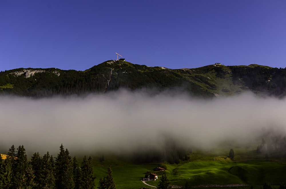 Campo de hierba verde cerca de la montaña verde bajo el cielo azul durante el día