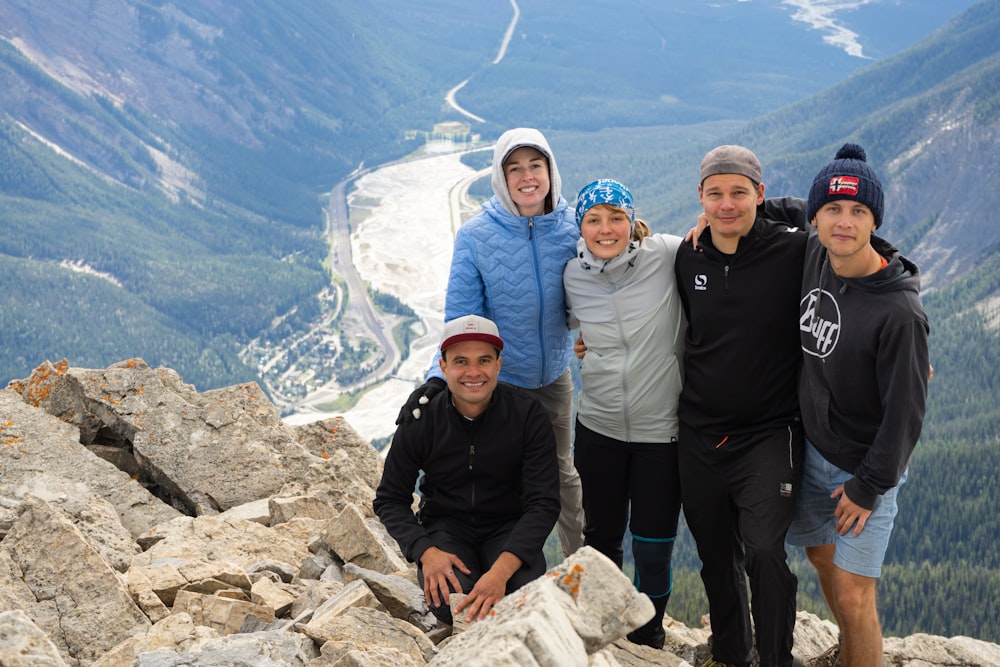 3 men and 2 women standing on rocky hill during daytime