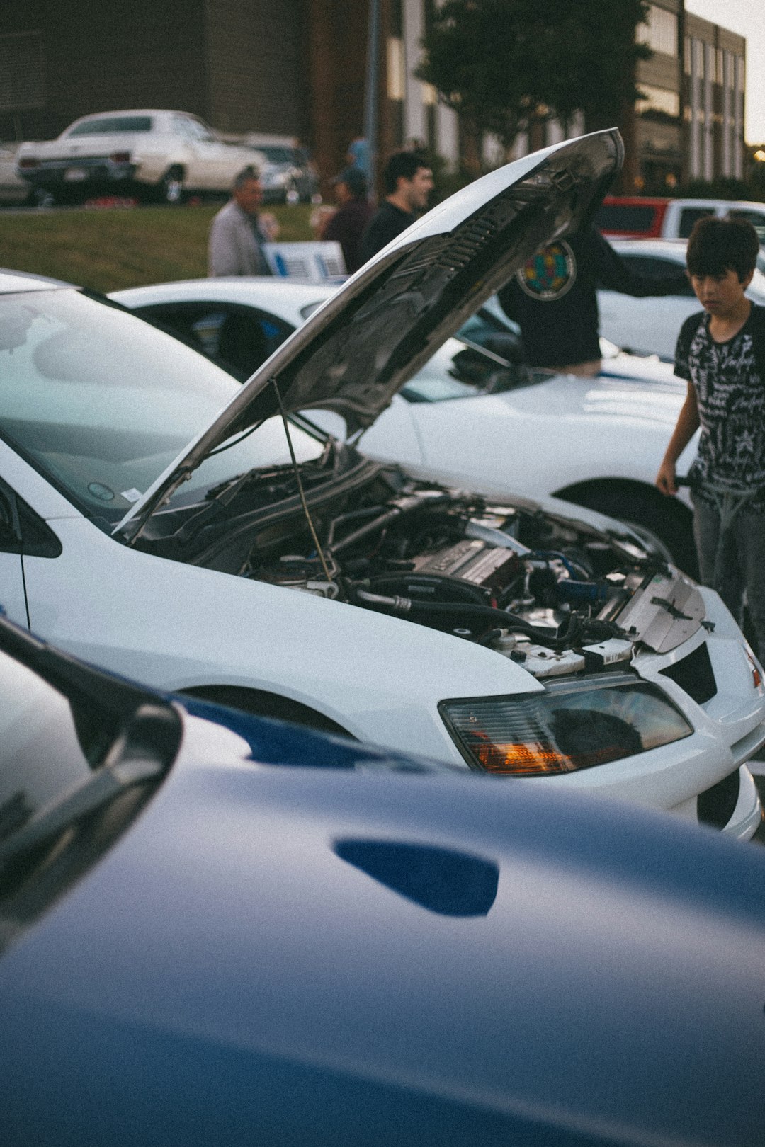 man in black and white plaid dress shirt standing beside white car during daytime