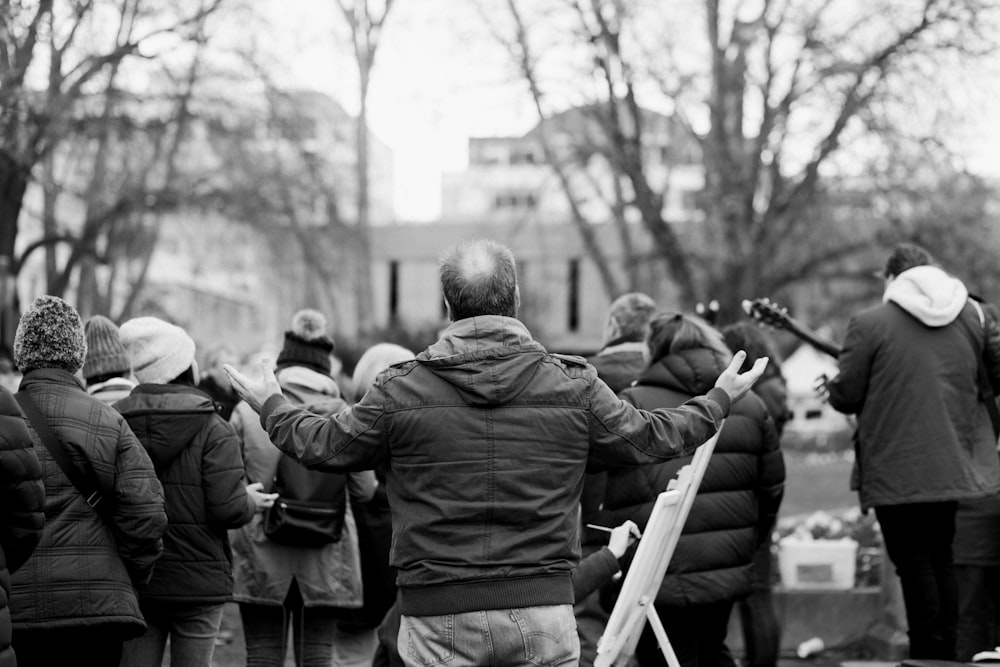 man in black jacket standing near people during daytime