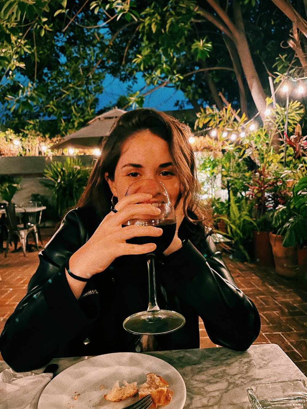 woman in black leather jacket drinking from clear drinking glass