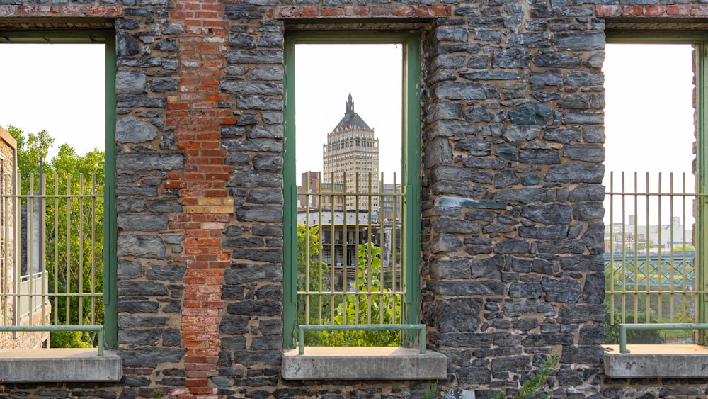 Portail de fenêtre en métal vert sur mur de briques brunes