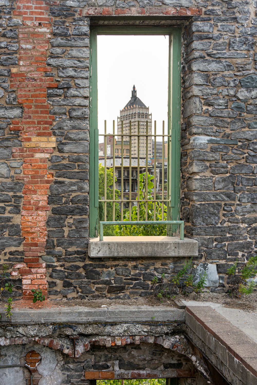 green metal gate on brown brick wall