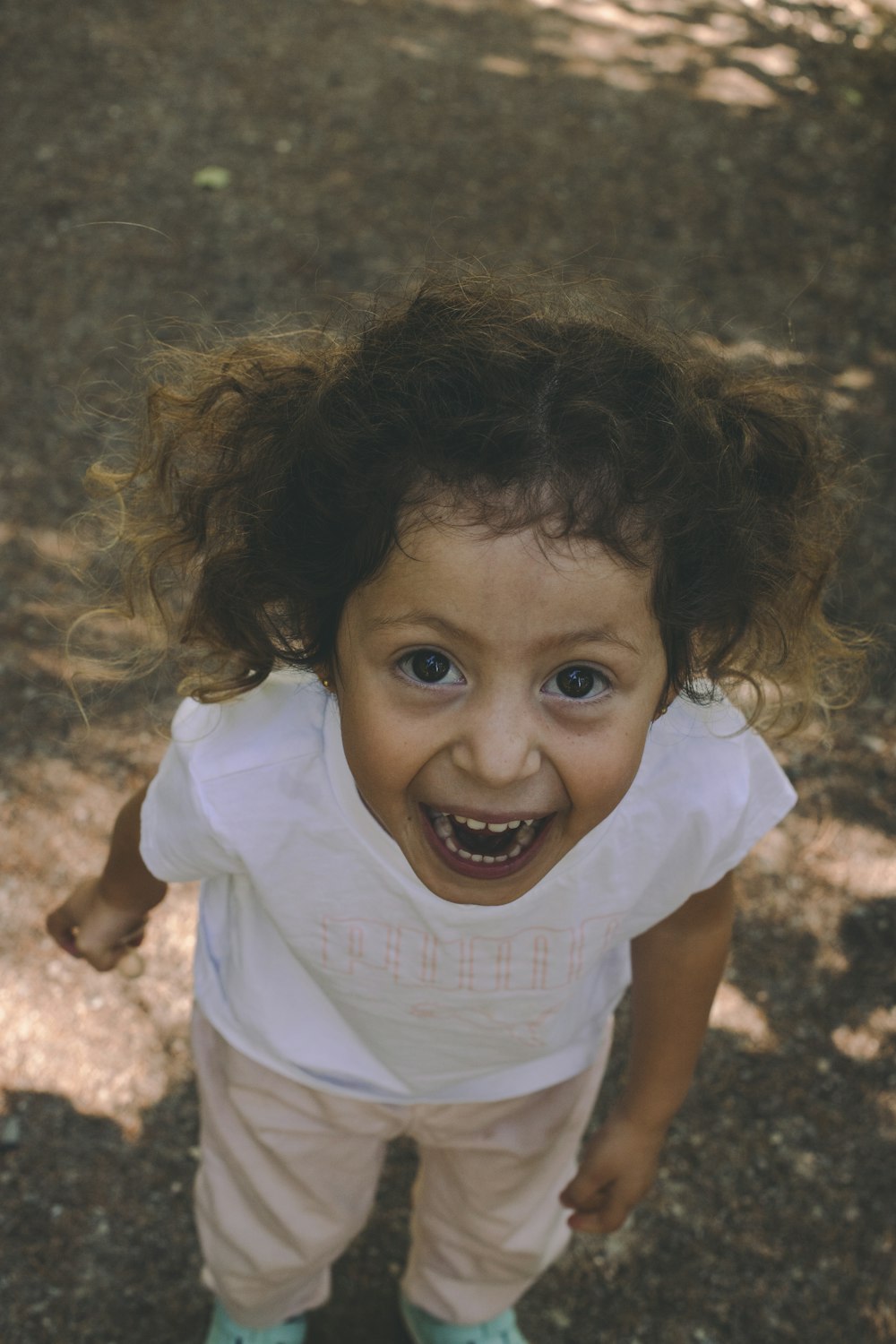 girl in white shirt standing on brown grass field