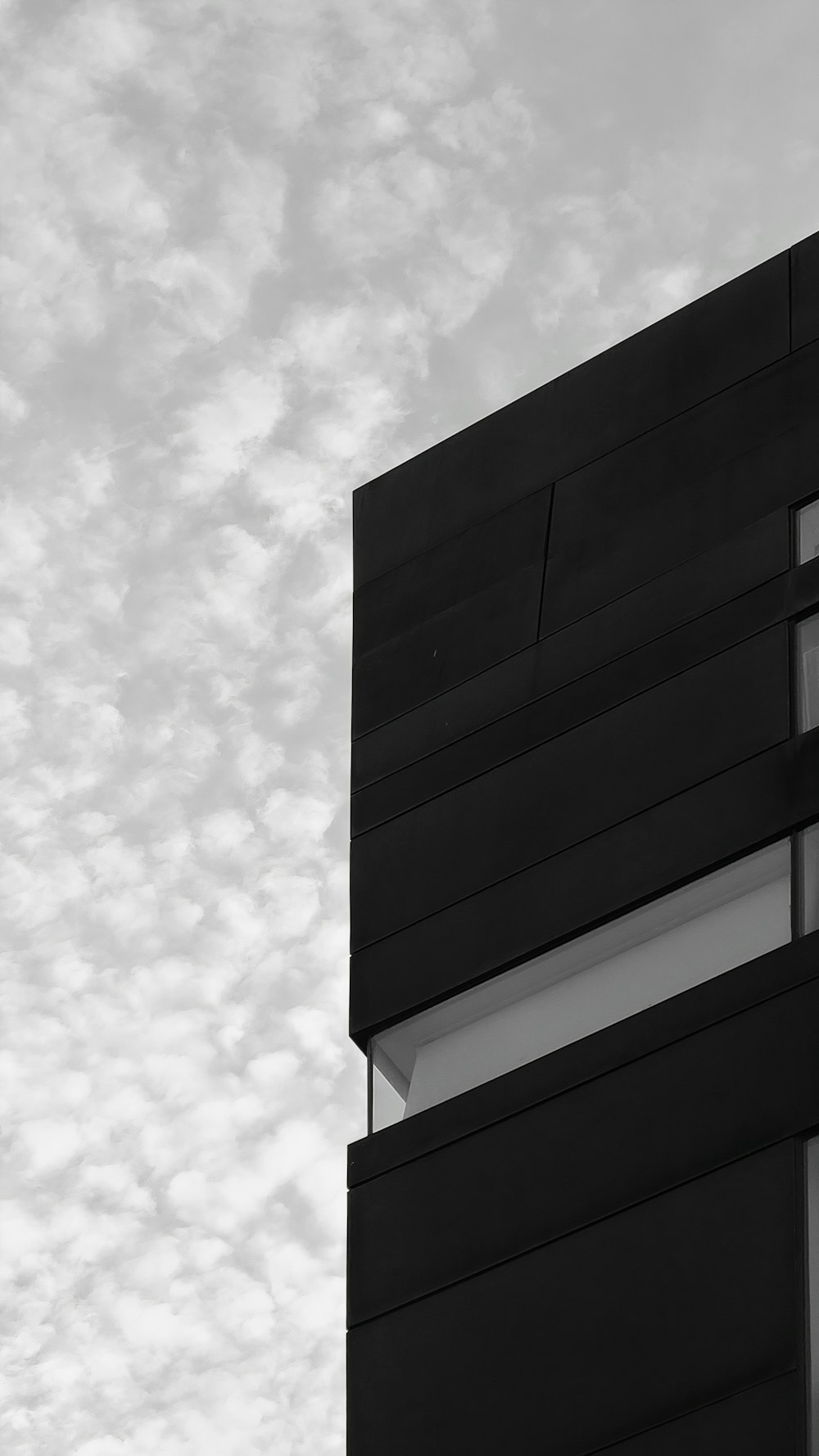 Edificio de hormigón blanco y negro bajo nubes blancas durante el día