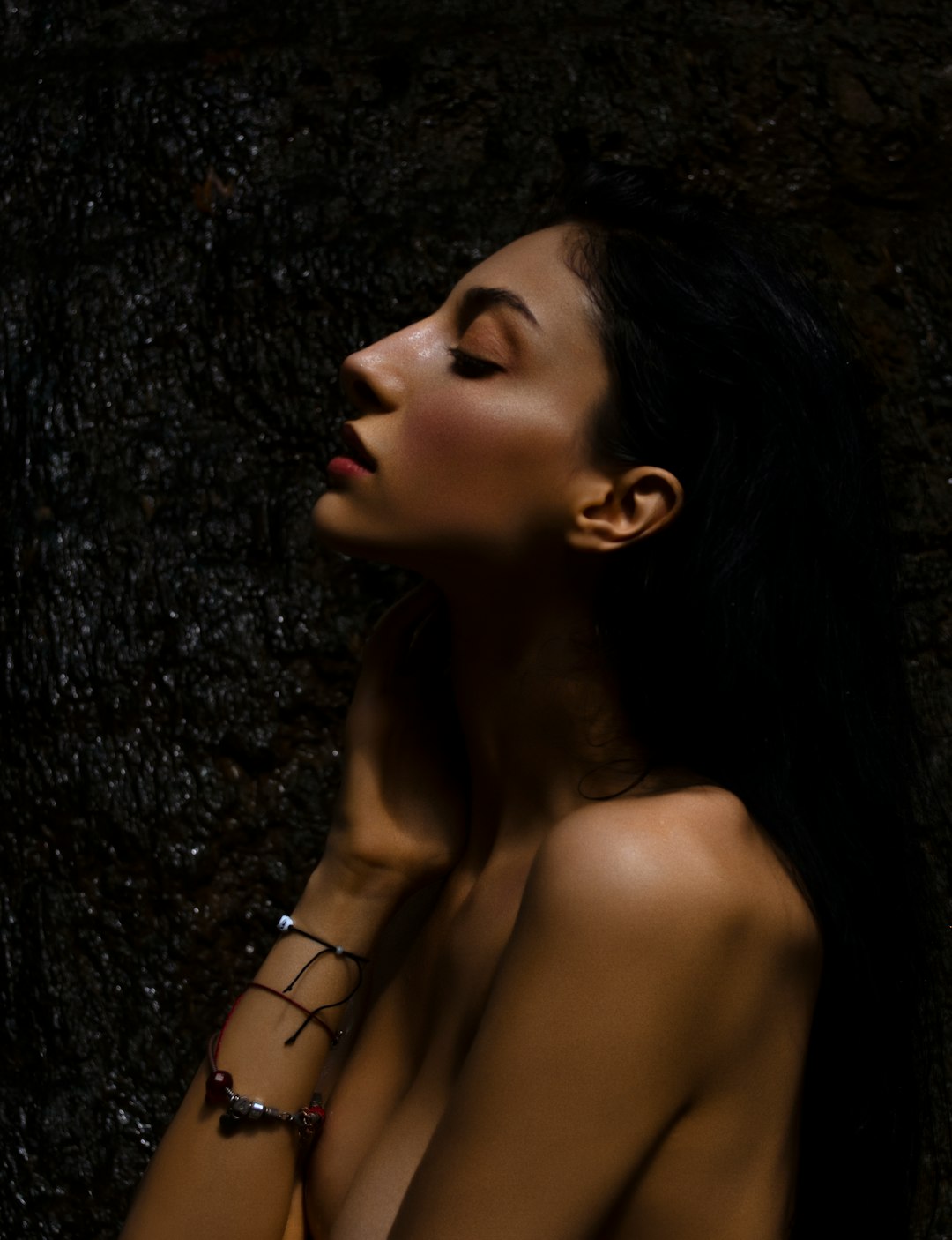 woman in black hair leaning on black wall