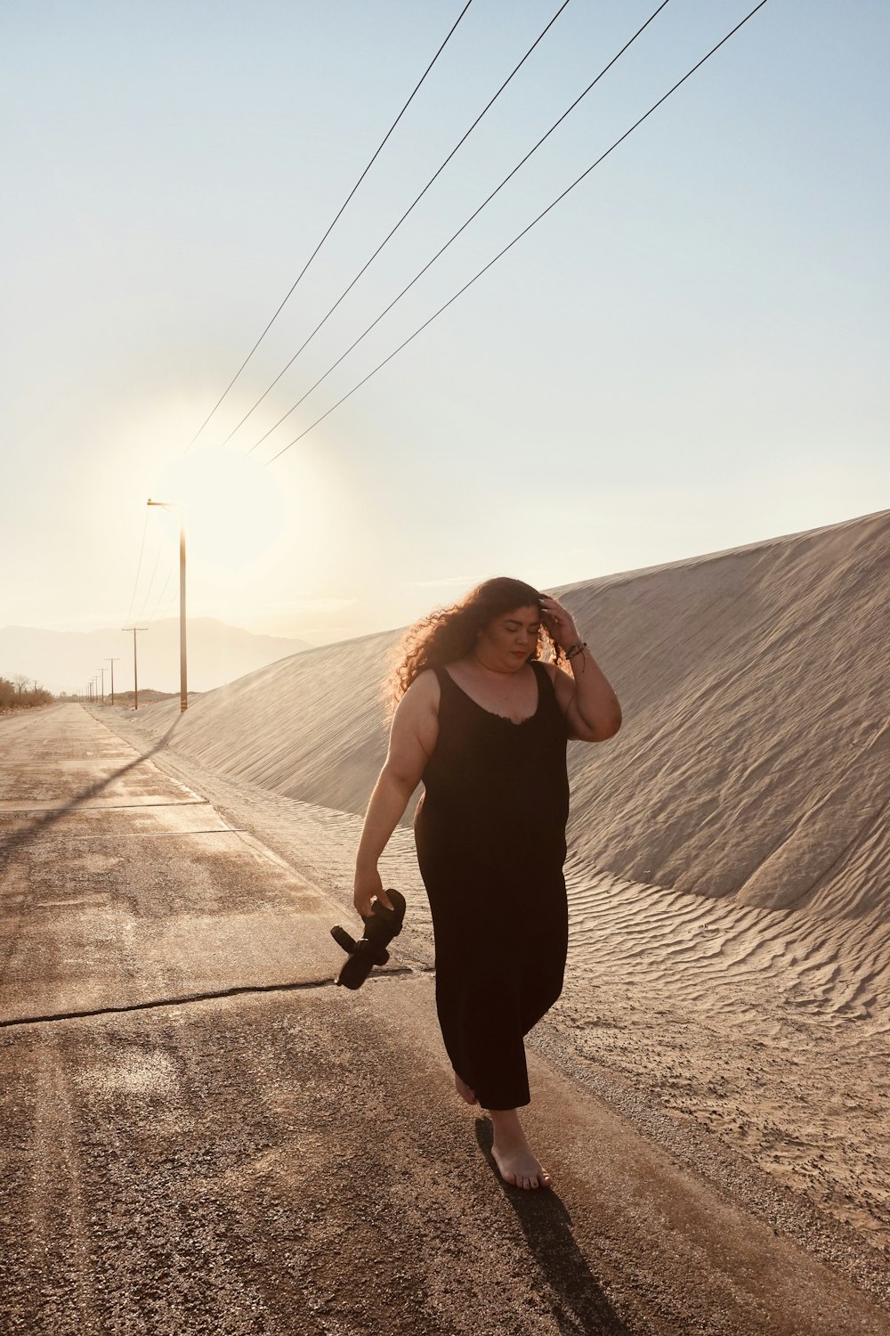 femme en débardeur noir et pantalon noir debout sur le sable brun pendant la journée