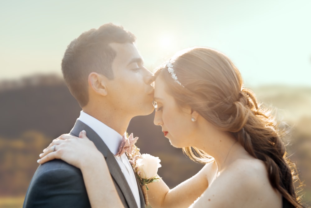 man in black suit kissing woman in white wedding dress