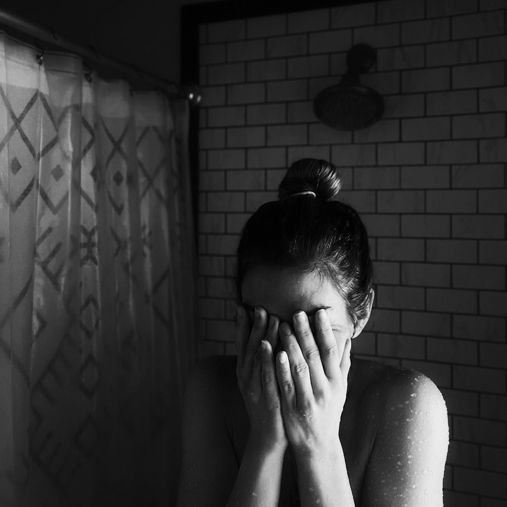 grayscale photo of woman covering her face with her hands