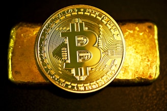 a bitcoin sitting on top of a gold bar