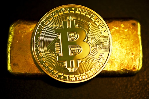 a bitcoin sitting on top of a gold bar