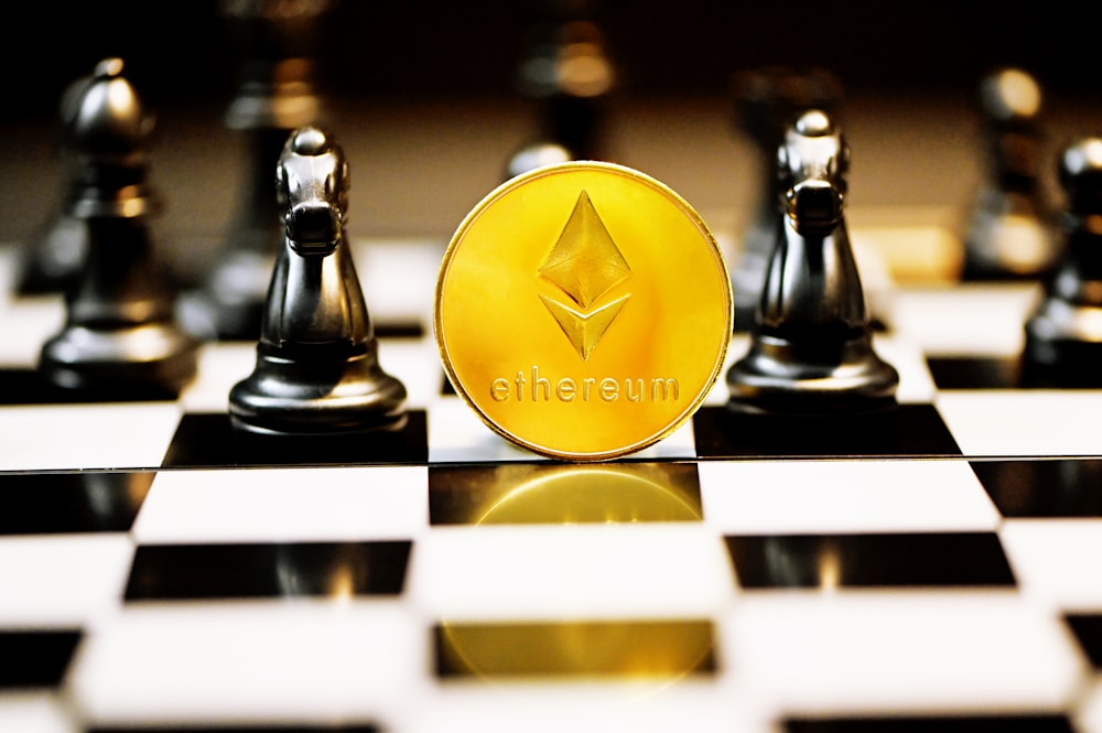 a gold ether coin sitting on top of a chess board