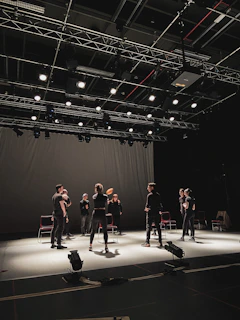 A lively theater stage with actors rehearsing under bright lights.