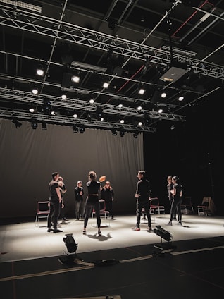 A vibrant theater rehearsal with actors practicing on stage under warm lighting.