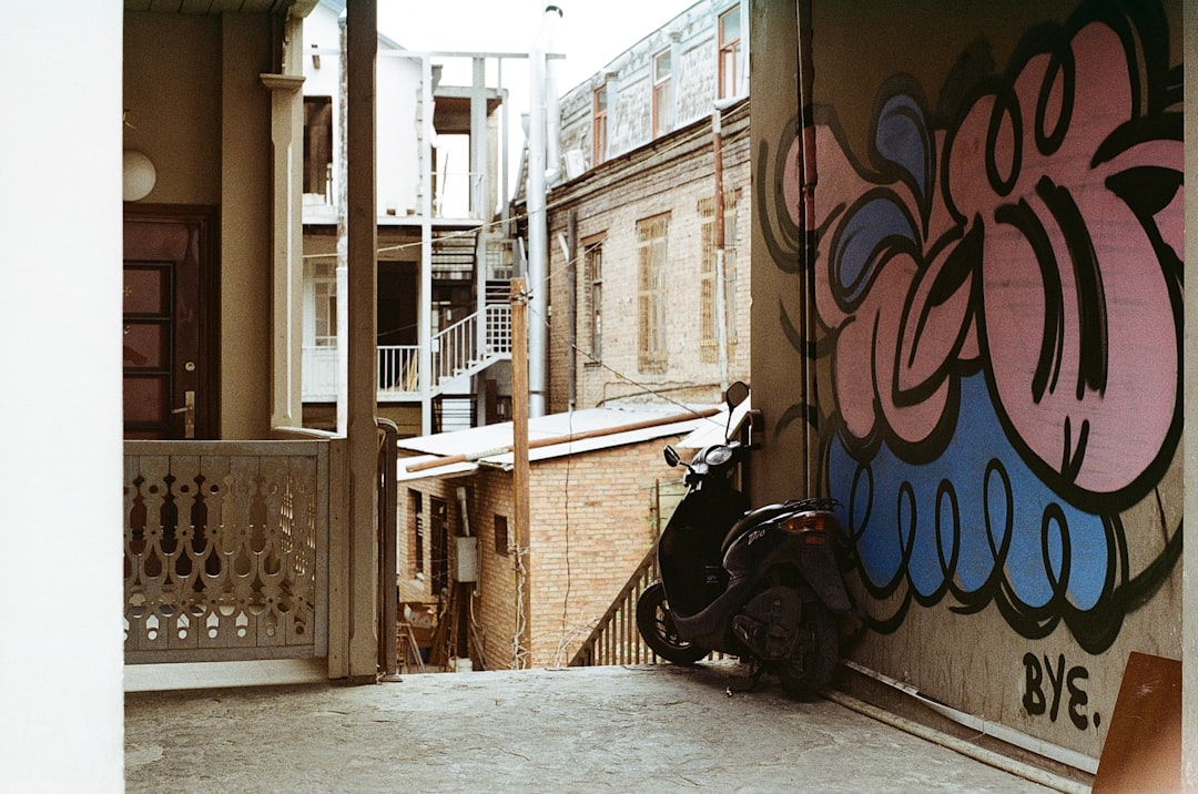 black motorcycle parked beside white wall with graffiti