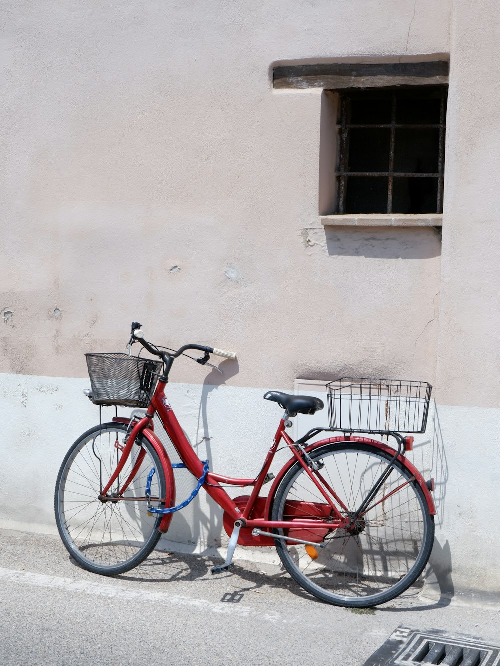 red city bike parked beside white concrete wall