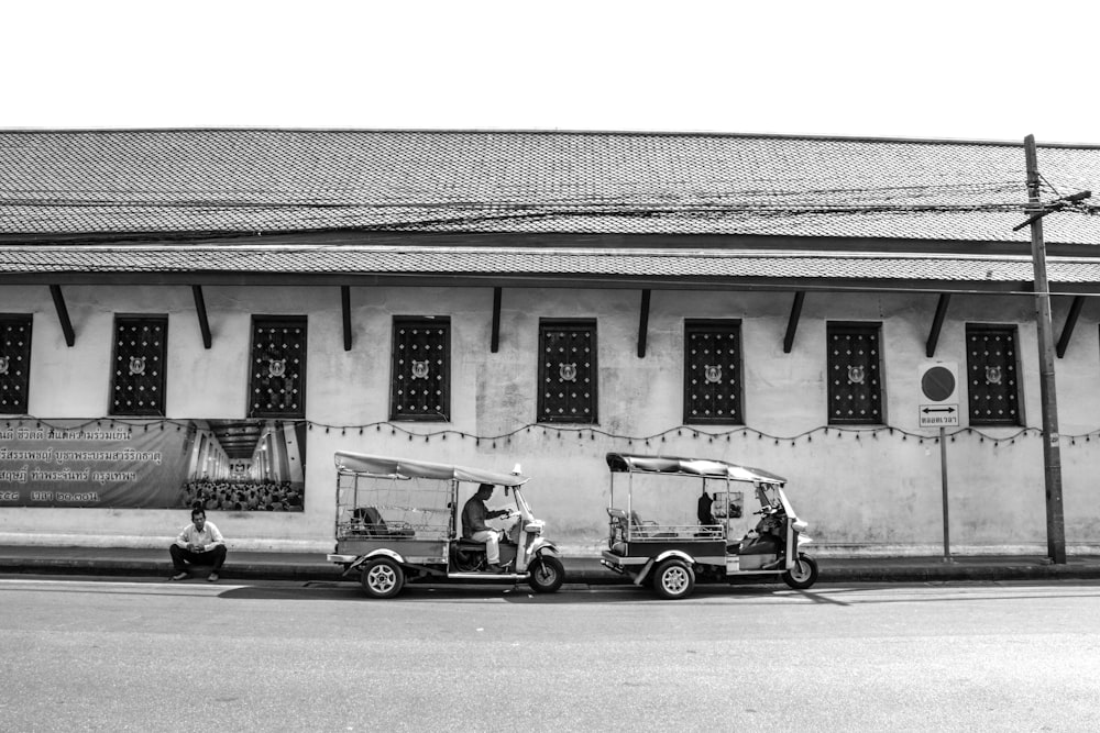 grayscale photo of 2 cars parked in front of building