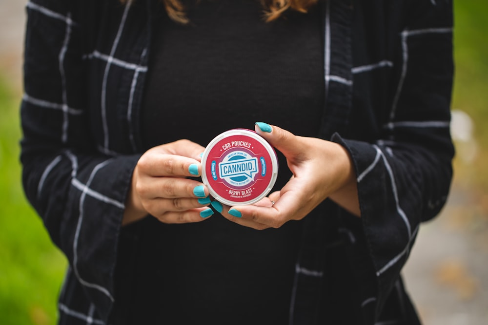 person holding blue and green round container