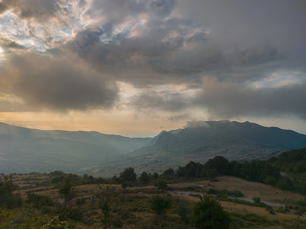 green trees and mountains under white clouds and blue sky during daytime