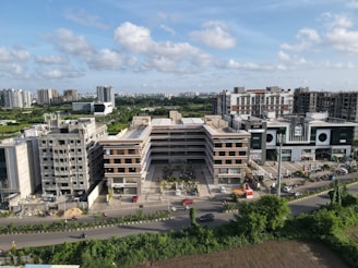 white concrete building near green trees under white clouds during daytime