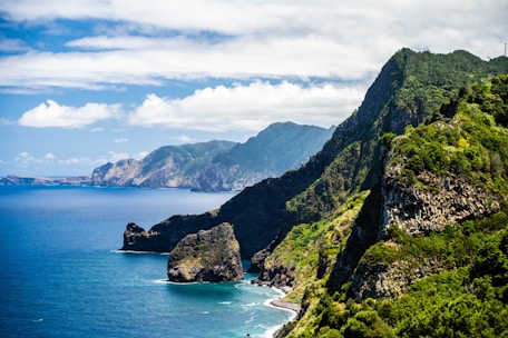 green mountain beside body of water under cloudy sky during daytime