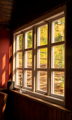 Soft sunlight filtering through a window onto a peaceful meditation corner with cushions and candles.