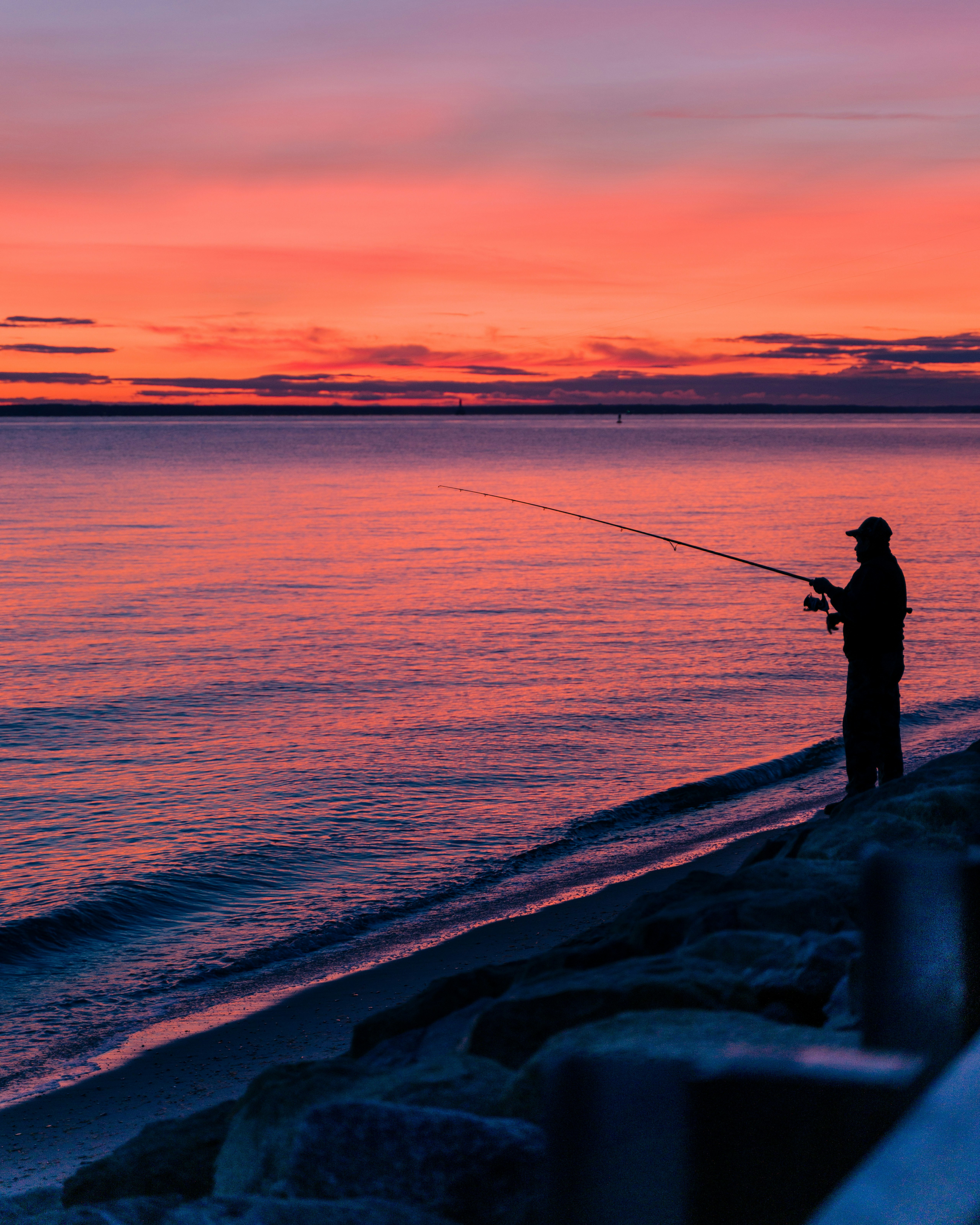 silhouette of man fishing on sea during sunset