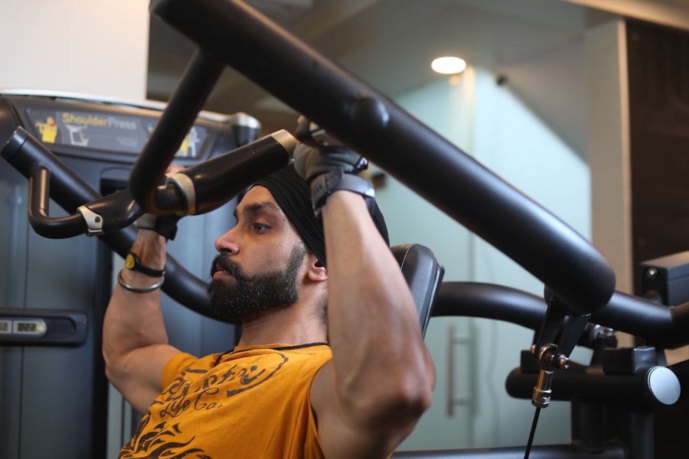 man in orange crew neck t-shirt holding black exercise equipment