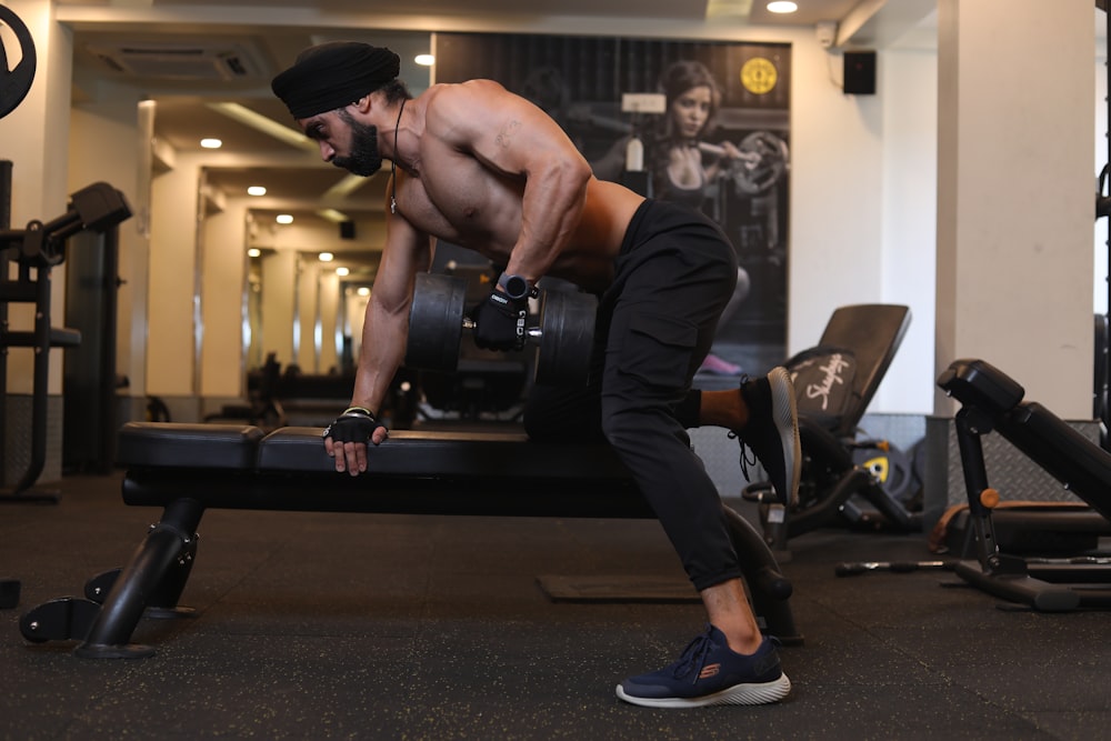 man in black pants and black nike shoes sitting on black bench press