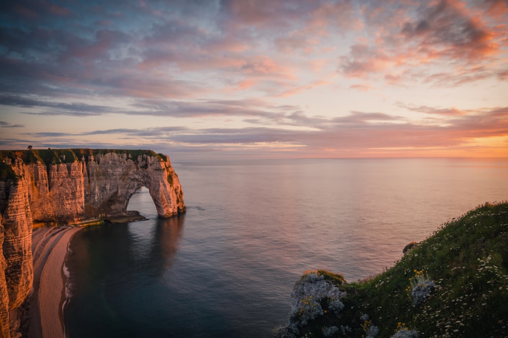 brown and green rock formation on sea under gray clouds during daytime