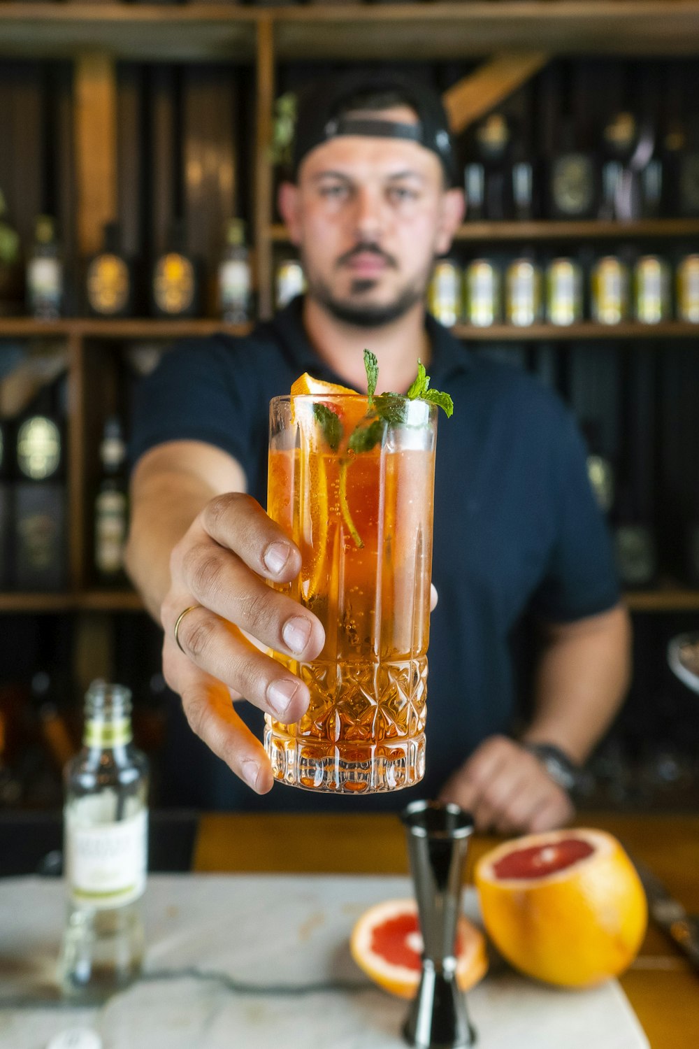 homme en t-shirt à col rond bleu tenant un verre à boire transparent avec un liquide orange