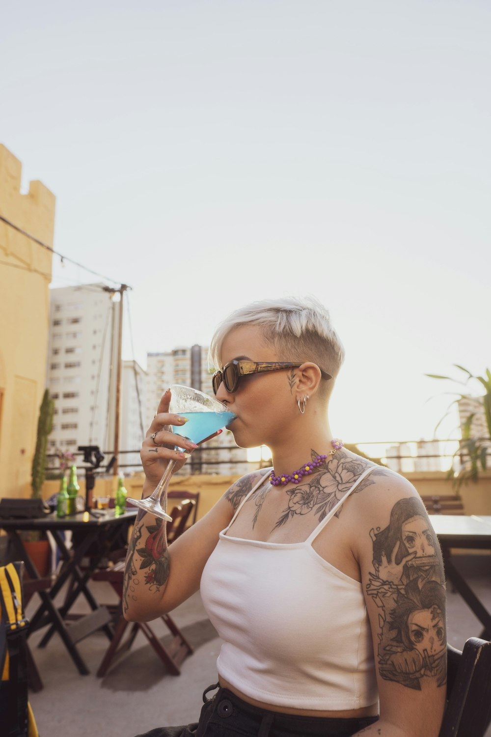 woman in white tank top wearing sunglasses holding cup
