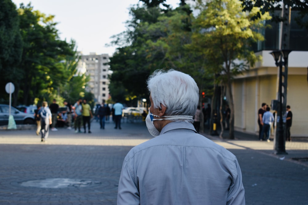 uomo in camicia grigia in piedi sulla strada durante il giorno