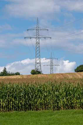 white and black electric tower under white clouds and blue sky during daytime