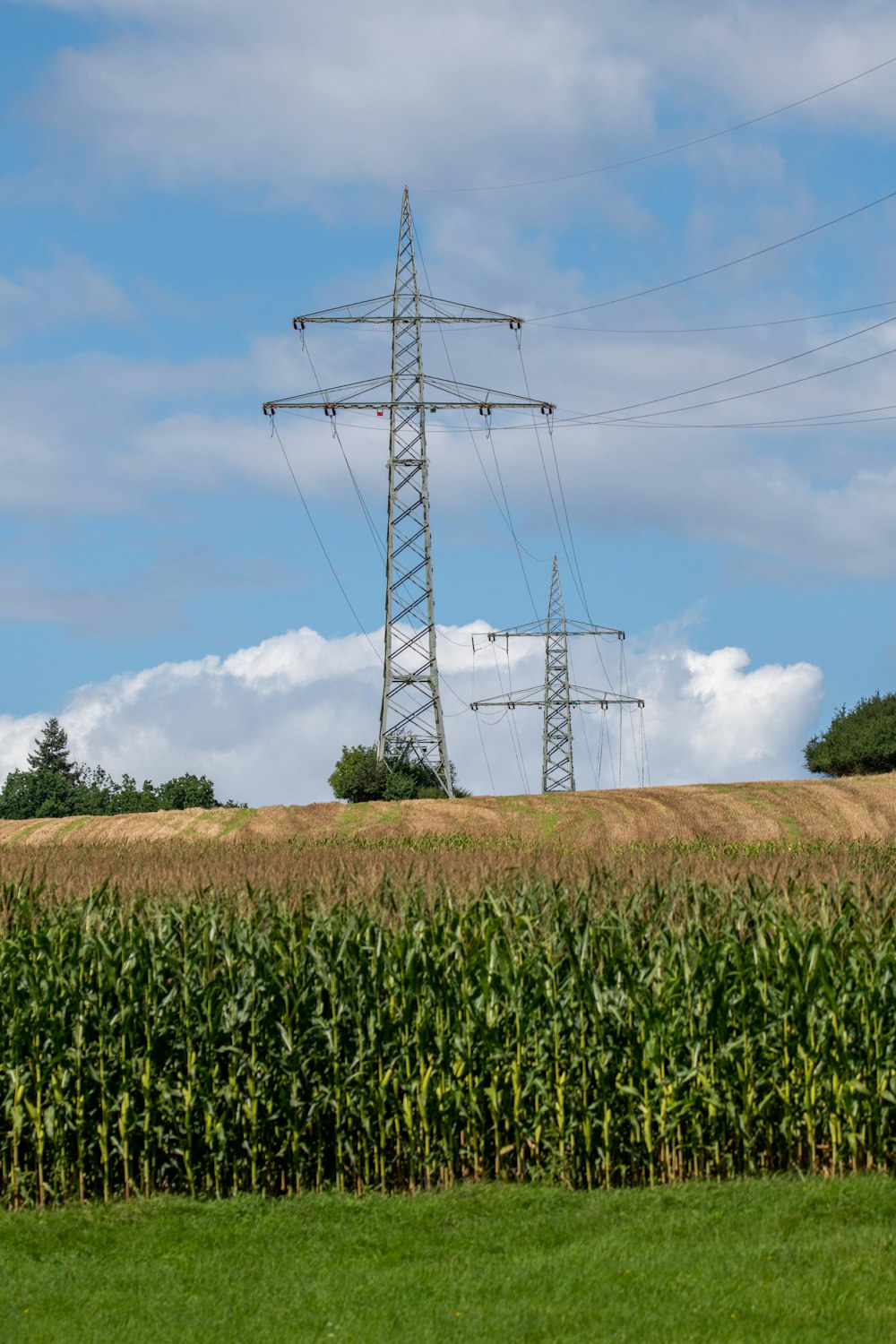 white and black electric tower under white clouds and blue sky during daytime