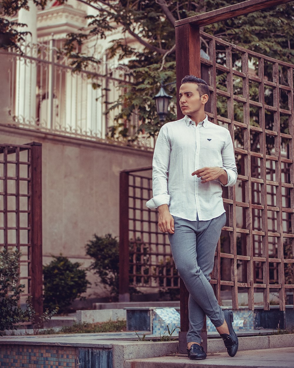 man in blue dress shirt and blue denim jeans standing on brown wooden window during daytime