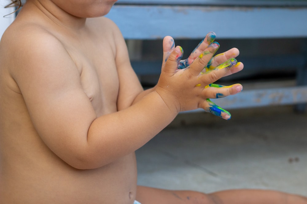 topless child with green blue and purple manicure