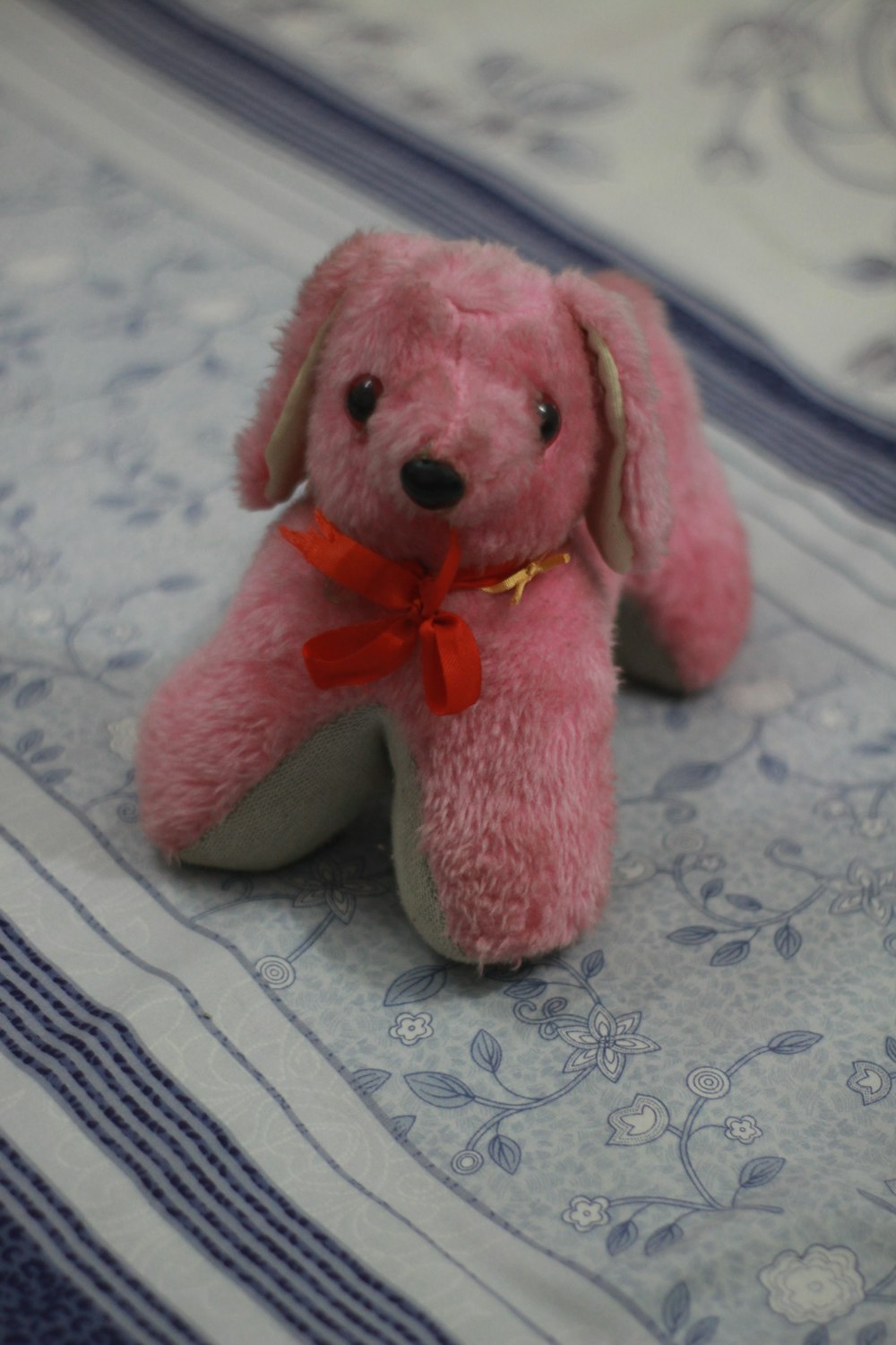 pink bear plush toy on white and blue textile