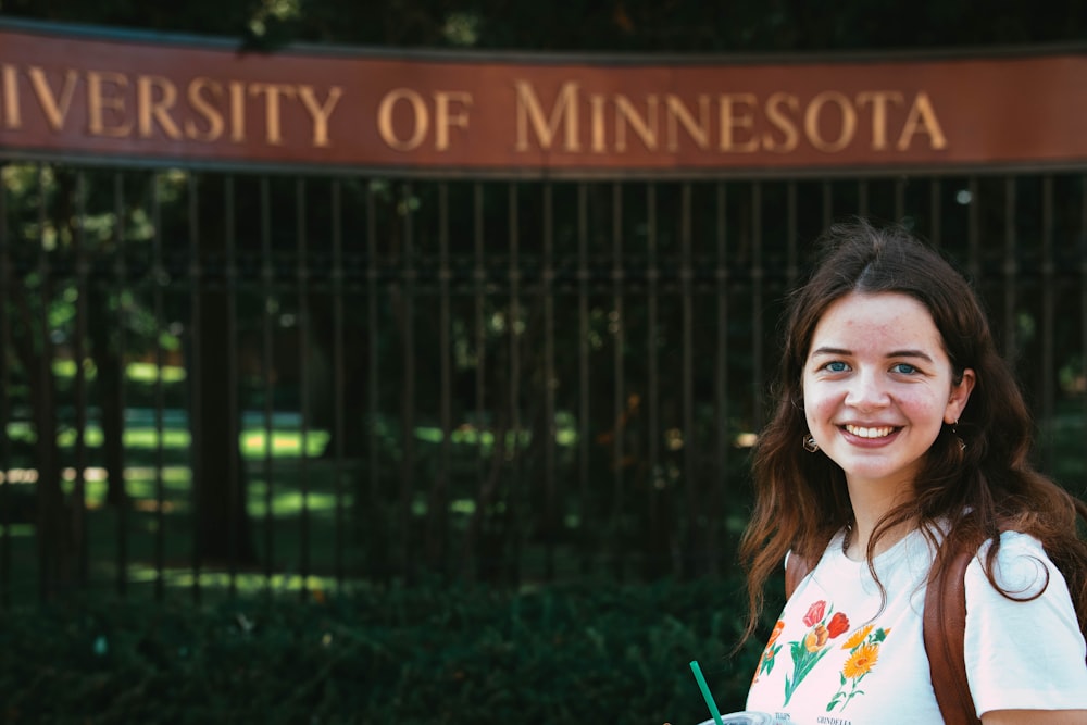 a woman standing in front of the university of minnesota sign