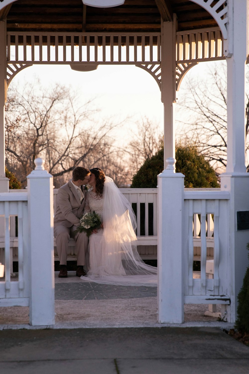 a bride and groom kissing under a gazebo