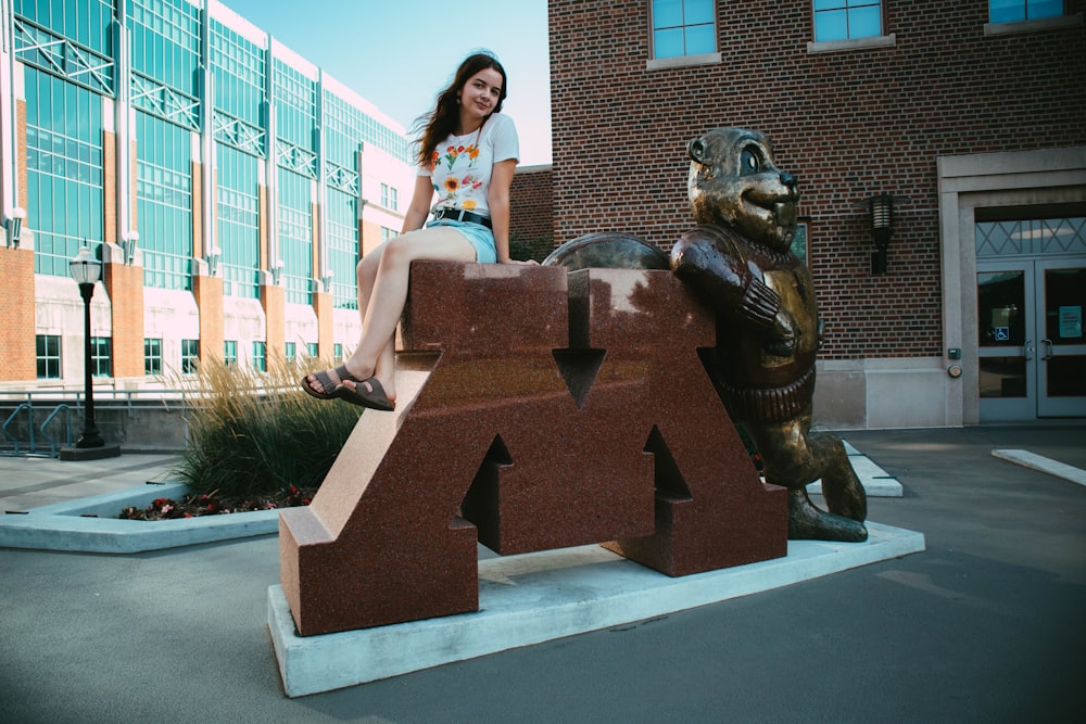 a woman sitting on top of a statue of a bear