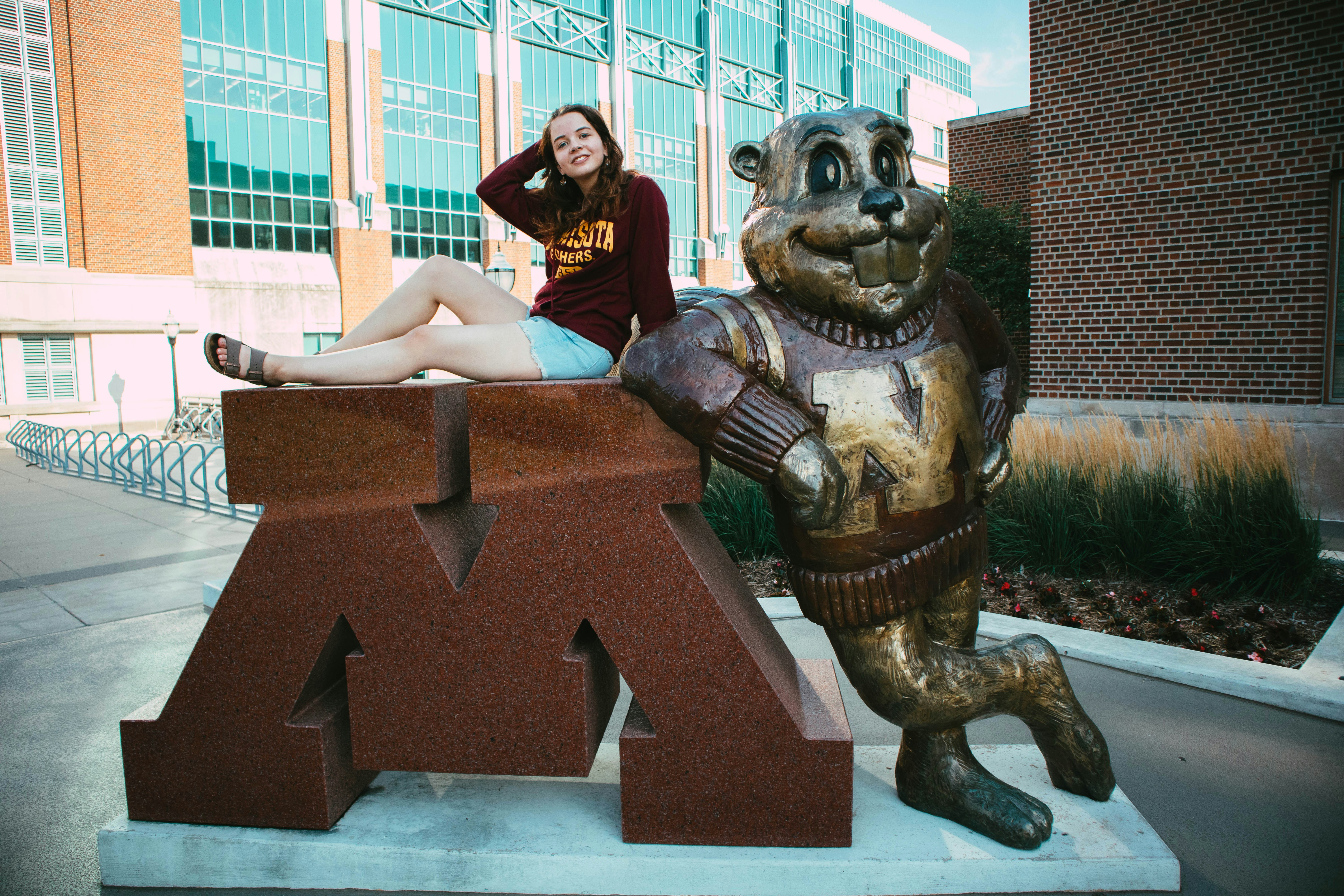 a woman sitting on top of a statue of a bear