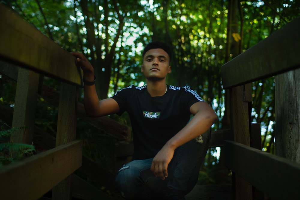 a man sitting on a wooden bridge in the woods