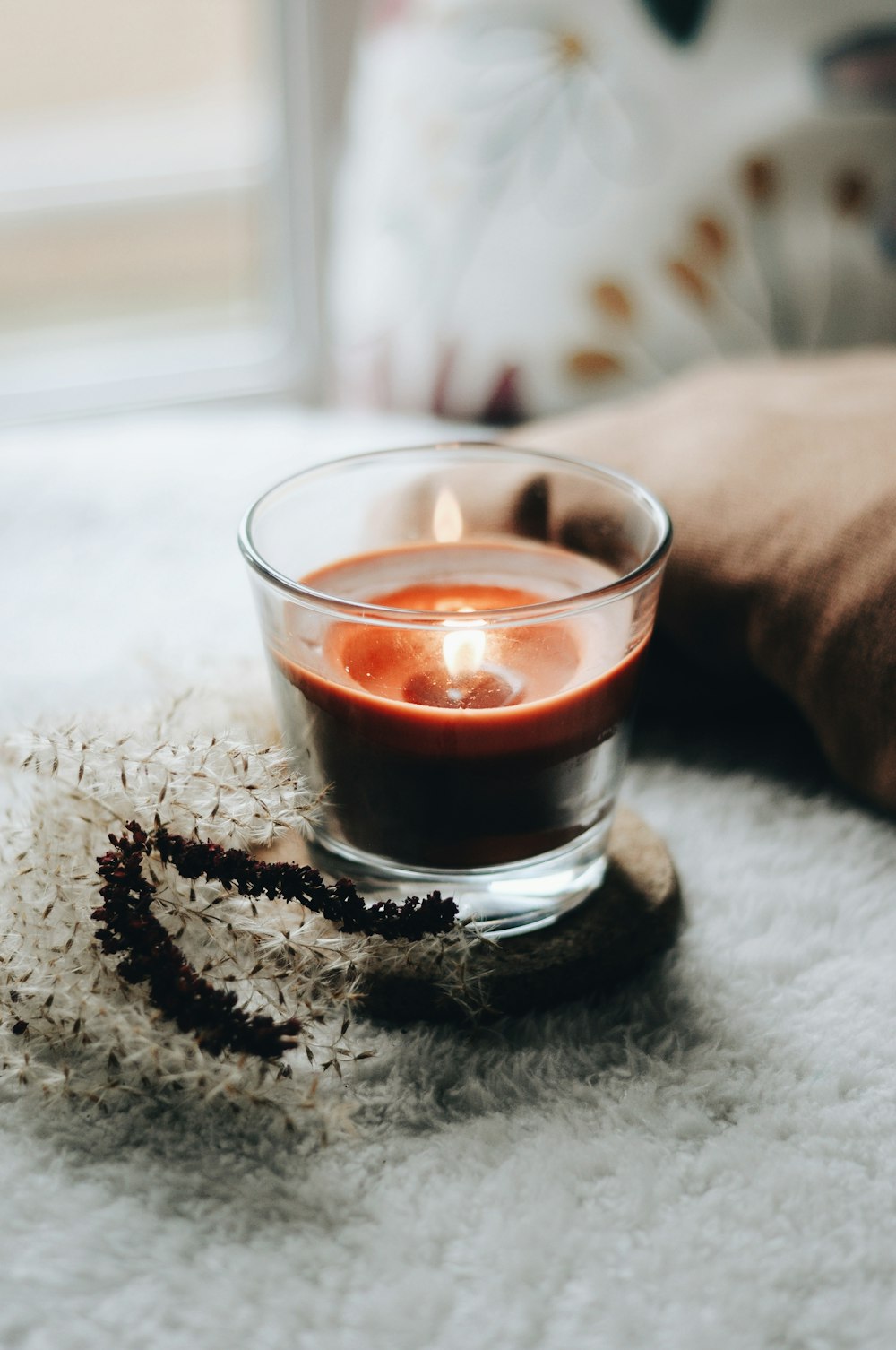 verre à boire transparent avec un liquide rouge sur textile blanc