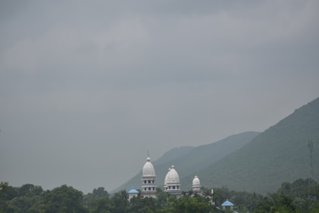 A serene landscape featuring a temple dedicated to Lord Shiva surrounded by lush greenery.