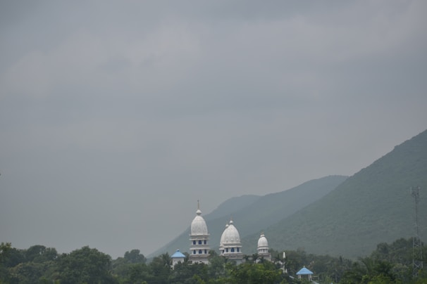 A serene view of a cab parked near a famous temple in Shirdi, surrounded by lush greenery.