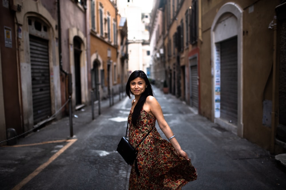 woman in black and brown floral dress standing on sidewalk during daytime