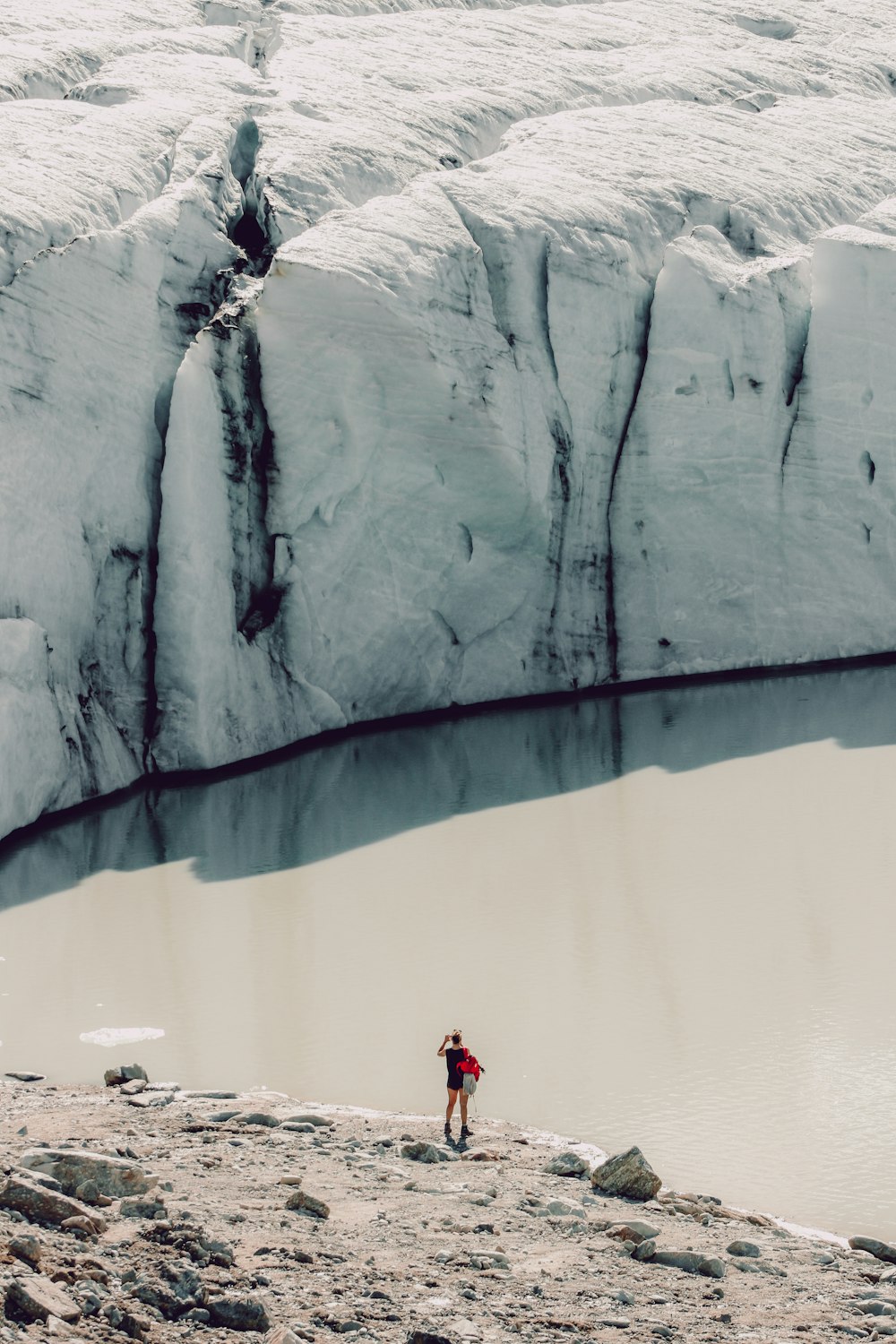 person in red jacket and black pants standing on white snow covered mountain during daytime