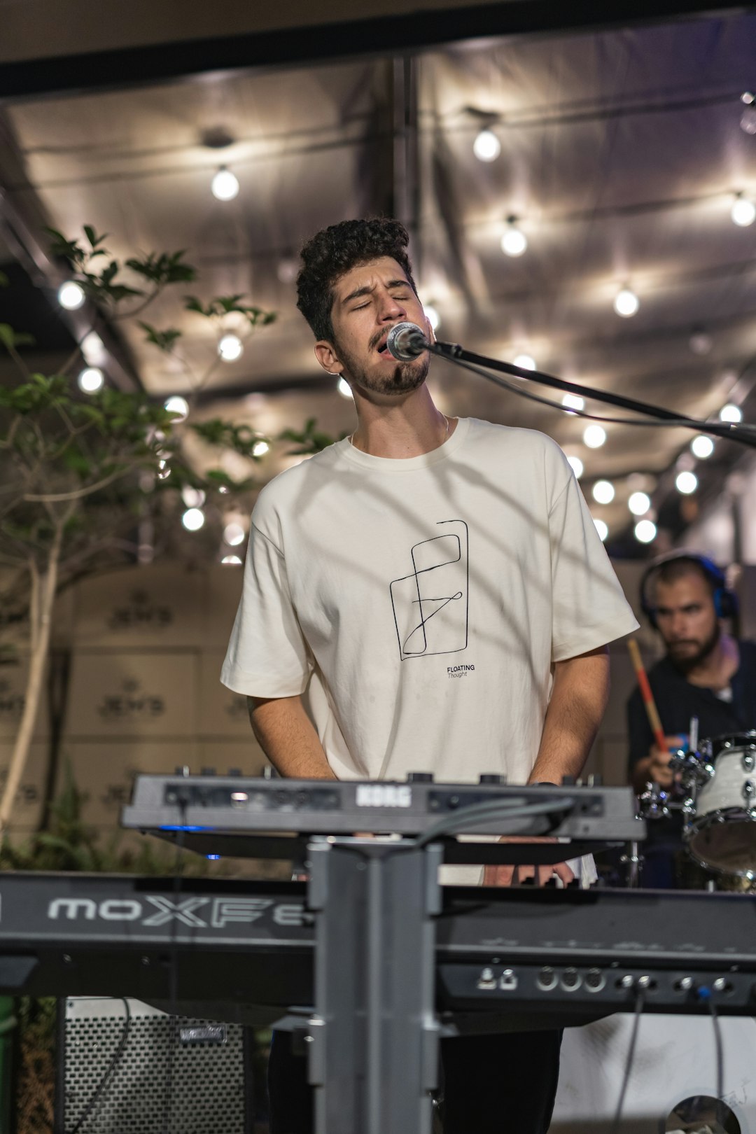 man in white crew neck t-shirt standing in front of microphone